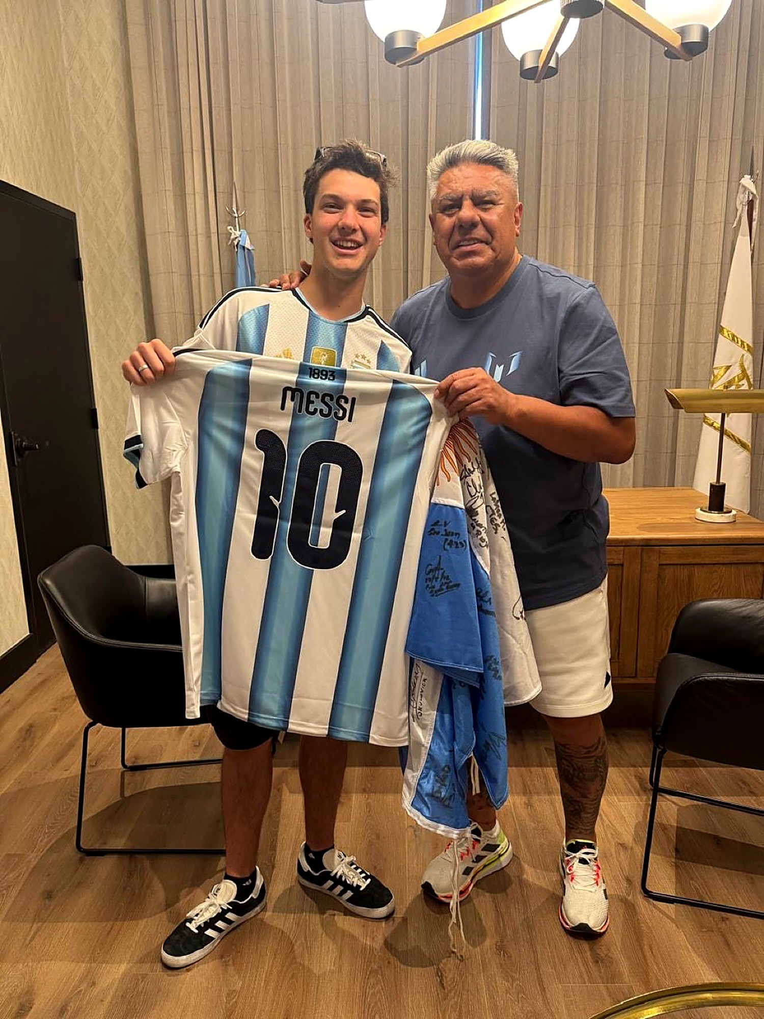 Juan junto al Presidente de la AFA sosteniendo la bandera firmada por las 23 provincias y la camiseta de la Selección Argentina